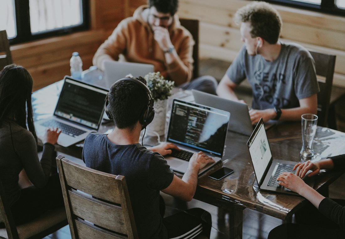 A small team working on laptops around a shared table